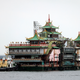 Hong Kong's Jumbo Floating Restaurant being pushed away on the water by tugboats. It's ornate but looks a little worse for wear.